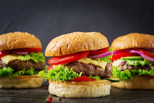 Trois Hamburger Avec Burger à La Viande De Boeuf Et Légumes Frais Sur Fond Sombre.