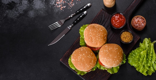 Trois hamburgers avec burger de viande de boeuf et légumes frais sur fond sombre