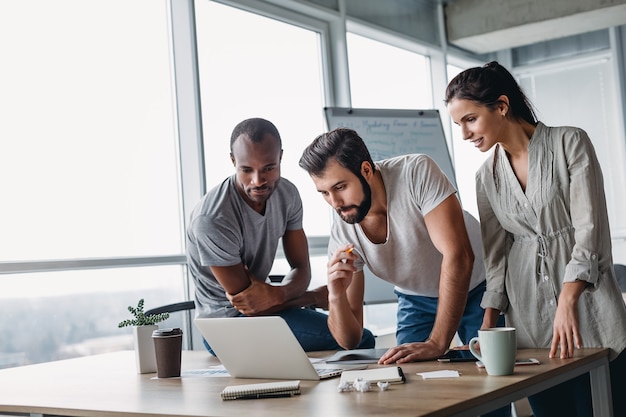 Trois hommes d'affaires divers parlant ensemble sur un ordinateur portable tout en travaillant dans la salle de réunion du bureau. Équipe d'affaires travaillant sur leur projet d'entreprise ensemble au bureau. Notion de succès