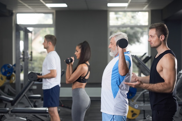 Trois hommes et une femme s'entraînant quotidiennement au gymnase.