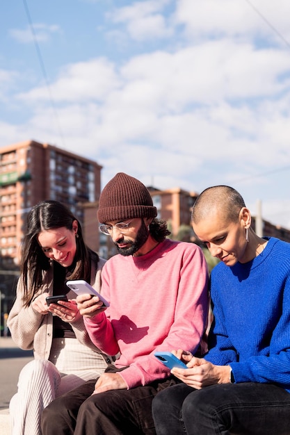 Trois jeunes adultes utilisant des téléphones portables en ville