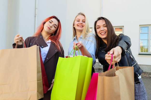 Trois jeunes amies avec des sacs colorés après le shopping