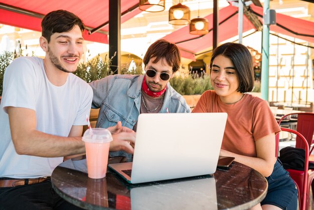 Trois jeunes amis à l'aide d'un ordinateur portable au café.