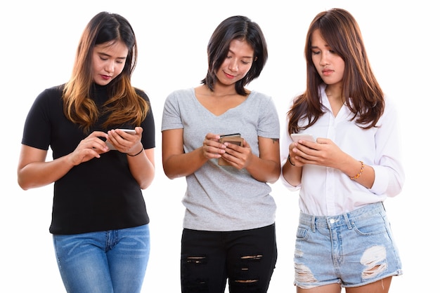 Trois jeunes amis de femme asiatique utilisant un téléphone mobile ensemble