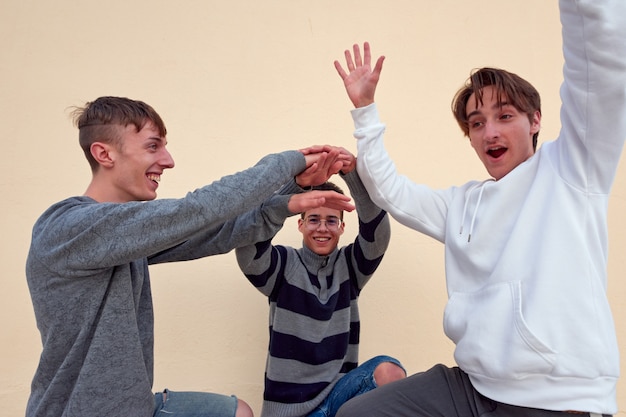 Trois jeunes amis joyeux dansant et s'amusant sur un fond uni