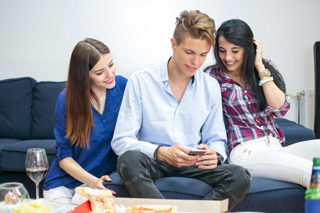 Trois jeunes amis utilisant un smartphone à la maison