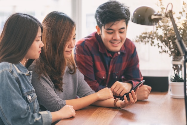 Trois Jeunes Asiatiques Utilisant Et Regardant Ensemble Le Même Téléphone Portable