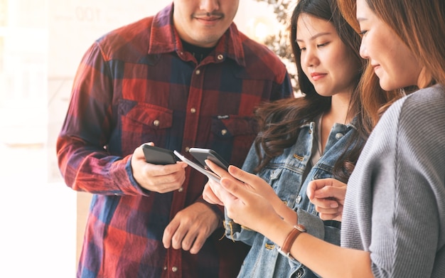 Trois jeunes asiatiques utilisant et regardant ensemble un téléphone portable et une tablette