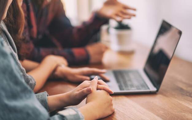 Trois jeunes asiatiques utilisant et regardant le même ordinateur portable lors d'une réunion