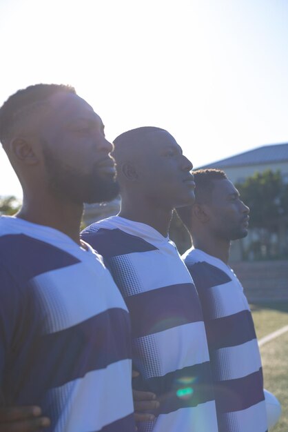 Photo trois jeunes athlètes afro-américains portant des vêtements de sport à rayures se tiennent ensemble sur le terrain