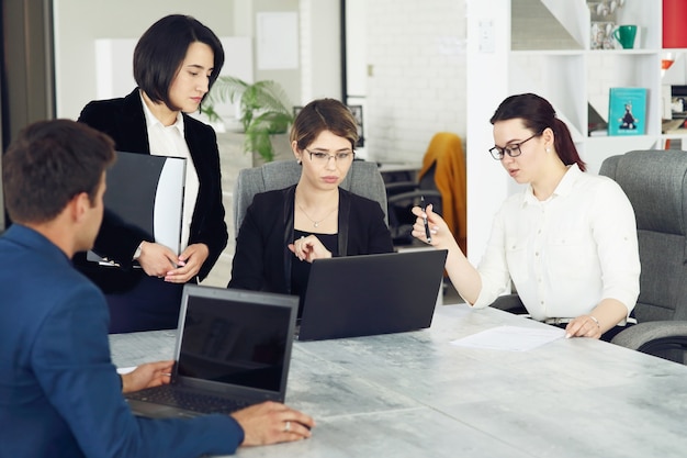 Trois jeunes femmes d'affaires prospères au bureau travaillant ensemble sur un projet