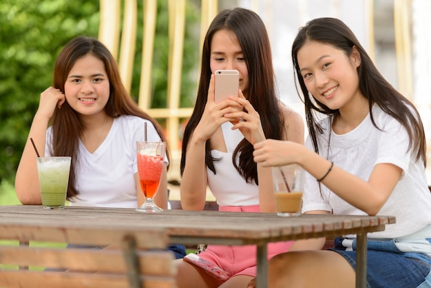 Trois jeunes femmes asiatiques heureux comme des amis se détendre ensemble au café en plein air