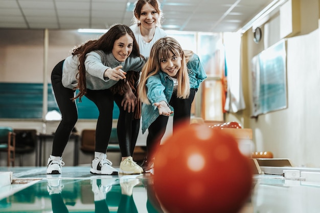 Trois jeunes femmes gaies s'amusant en jouant au bowling et en passant du temps ensemble.