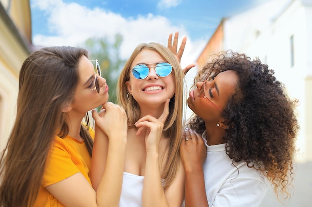 Trois jeunes femmes hipster souriantes en vêtements d'été posant dans la rue Femme montrant des émotions positives du visage