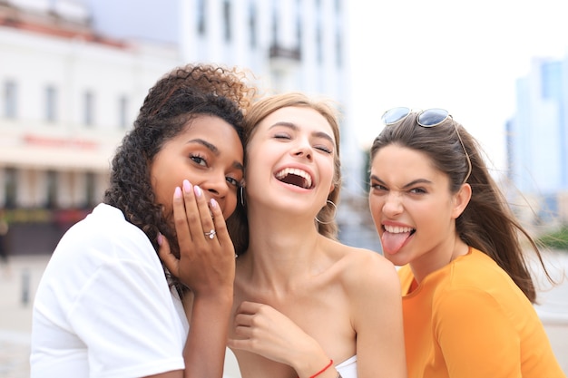 Trois jeunes femmes hipster souriantes en vêtements d'été posant dans la rue. Femme montrant des émotions positives pour le visage.