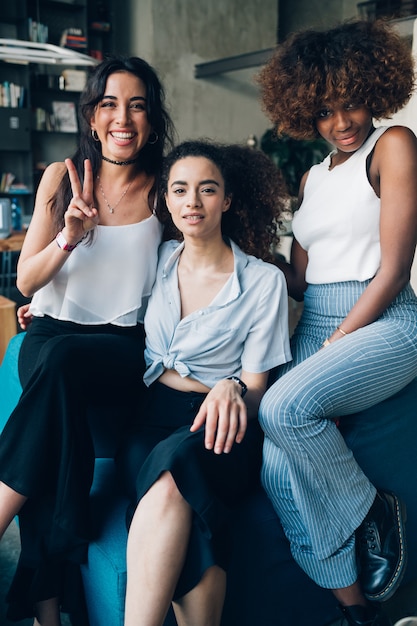 Trois jeunes femmes multiraciales assis ensemble dans un loft moderne et à la recherche