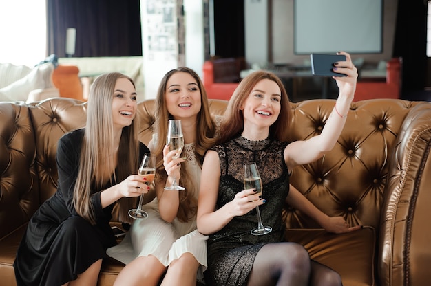 Trois jeunes filles font une photo selfie dans un restaurant.