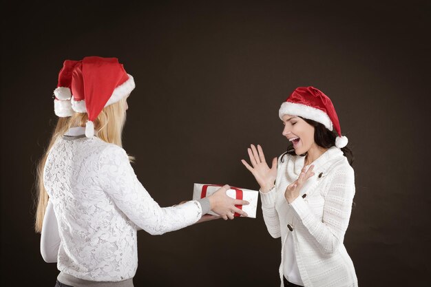 Trois jeunes filles heureuses en costume de père noël avec noël