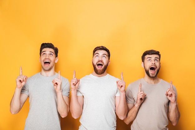 Trois jeunes hommes excités pointant vers l'espace de copie