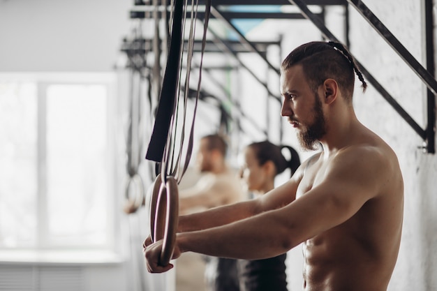 Trois jeunes hommes et femmes adultes faisant des tractions sur des anneaux