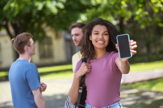 Trois jeunes avec des smartphones en mains passent du temps dans le parc