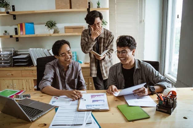 Trois jeunes travailleurs asiatiques discutant de leur produit