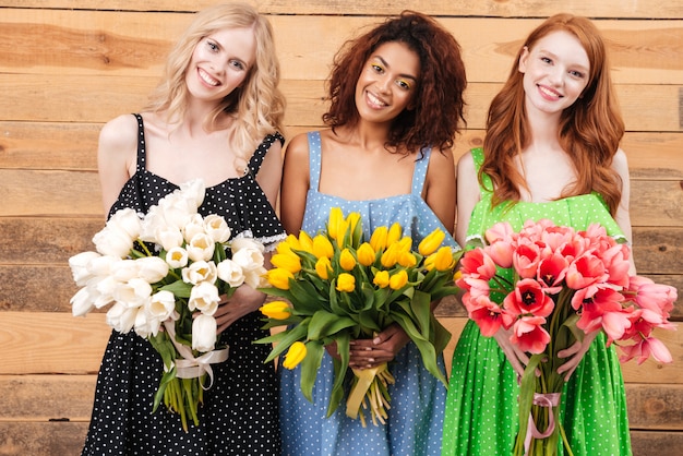 Trois jolies femmes tenant des bouquets de fleurs