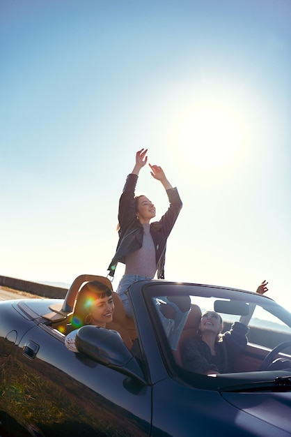 Trois jolies jeunes femmes en cabriolet en voyage par une belle journée d'été