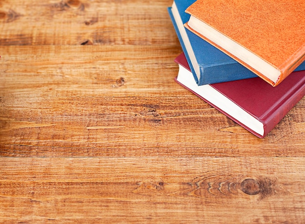 Trois livres multicolores se trouvent sur une table en bois Vue d'en haut