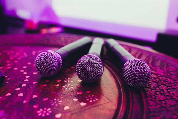 Trois microphones en groupe sur une table rouge avec fond.