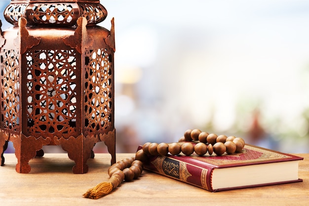 Photo trois mois.livre saint islamique coran avec chapelet sous une lumière douce.