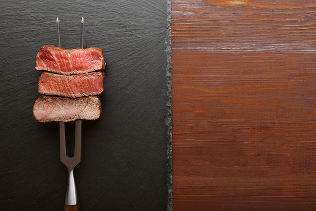 Trois morceaux de viande sur une fourchette pour la viande. trois types de viande à rôtir, rare, moyenne, bien cuite.