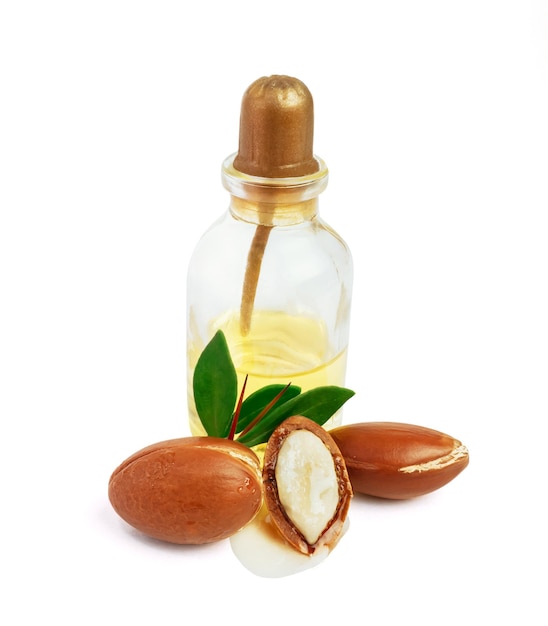 Photo trois noix d'argan avec des feuilles vertes bouteilles en verre sur fond blanc isolé noix d'argan hachée avec