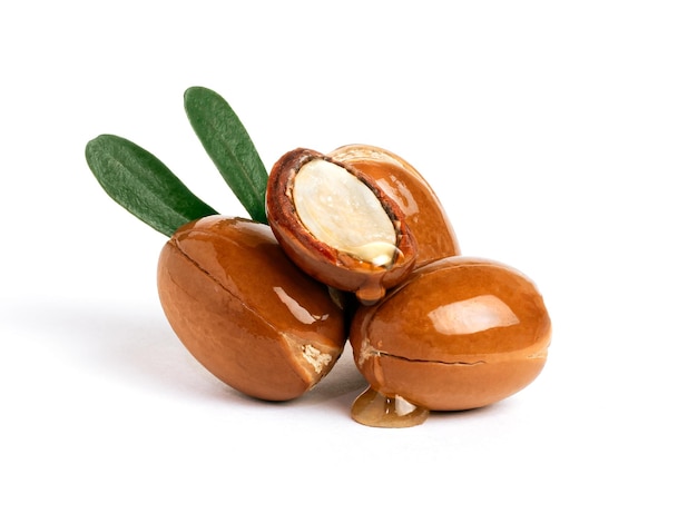 Trois noix d'argan avec des feuilles vertes sur un fond blanc isolé