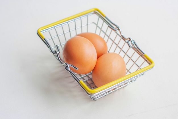 Trois œufs bruns dans un panier d'épicerie