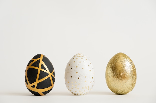 Trois oeufs décorés en or de Pâques. Concept de Pâques minimal