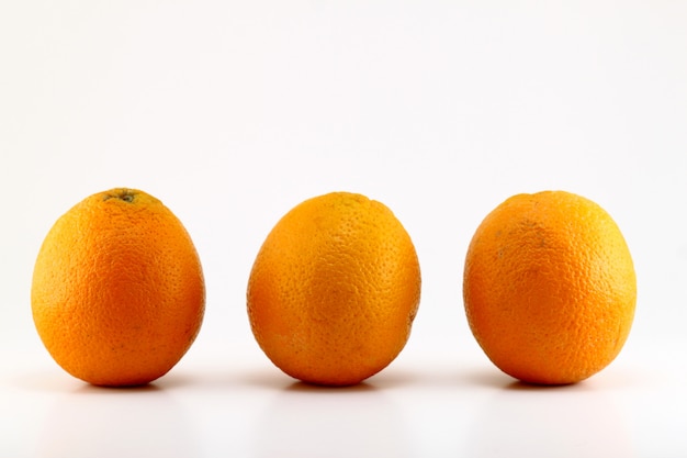 Trois oranges mûres isolés sur blanc