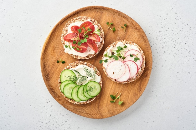 trois pains au sarrasin croustillants sans gluten avec fromage à la crème, radis, tomate, concombre et microgreen