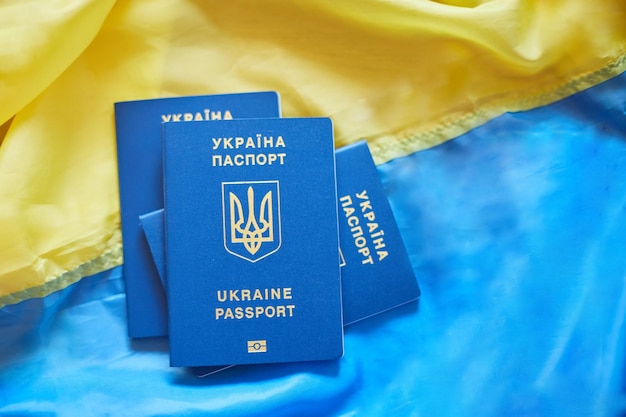 Trois passeports biométriques ukrainiens sur le drapeau de l'immigration ukrainienne parce que la guerre