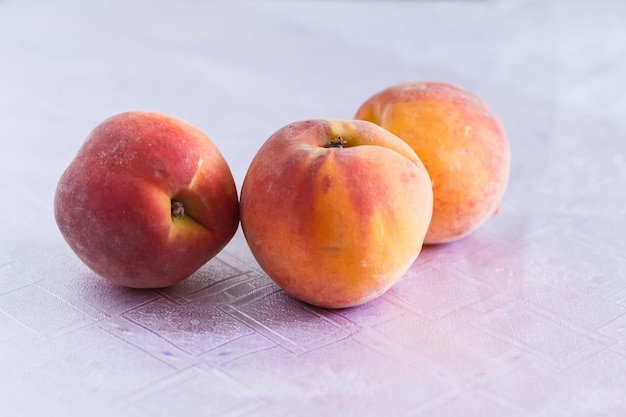 Trois pêches sur une nappe blanche