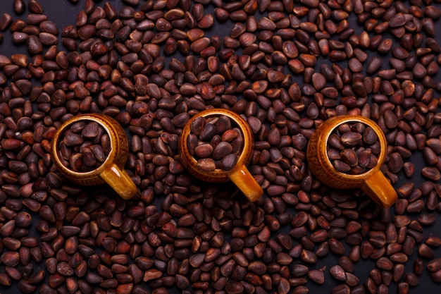 Trois petite tasse de noix de pin dans des coquillages sur ardoise noire Espace copie Vue de dessus