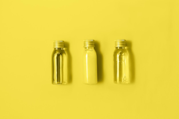 Trois petites bouteilles de mock-up avec des produits cosmétiques spa de couleur jaune à la mode