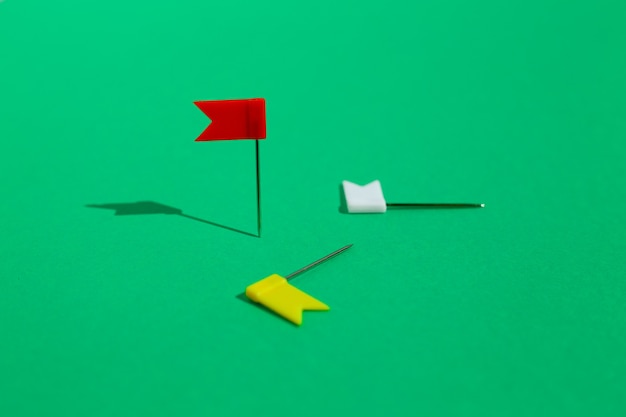 Trois petites épingles colorées épinglées sur une surface verte. Concept d'affaires ou de voyage. Les buts .