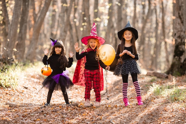 Trois petites filles en costumes de sorcière rient évoquent une promenade à travers la forêt d'automne