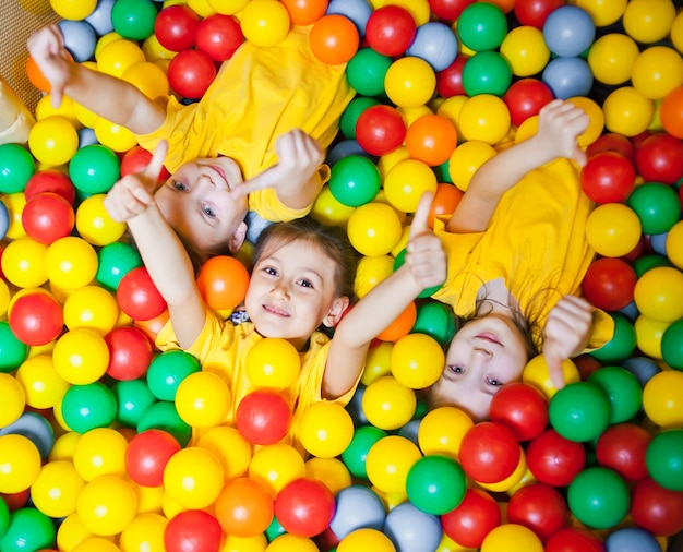 Trois petits enfants heureux dans la piscine à balles souriant