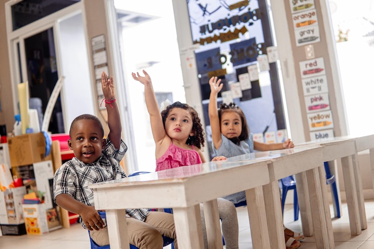 Photo trois petits enfants avec les mains en l'air dans une classe