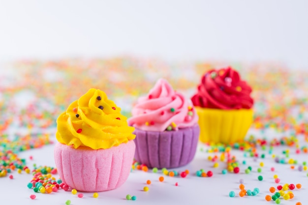 Trois petits gâteaux au sucre multicolores miniatures sur fond clair avec des paillettes