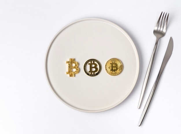 Trois pièces d'or bitcoin servi sur une assiette vide blanche
