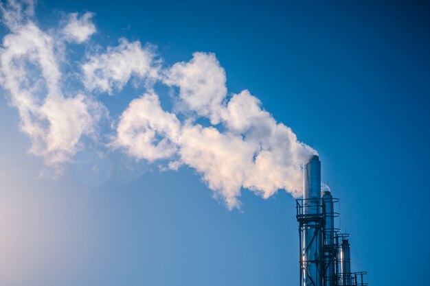 Trois pipes fumant une fumée blanche d&#39;affilée sur un ciel bleu.