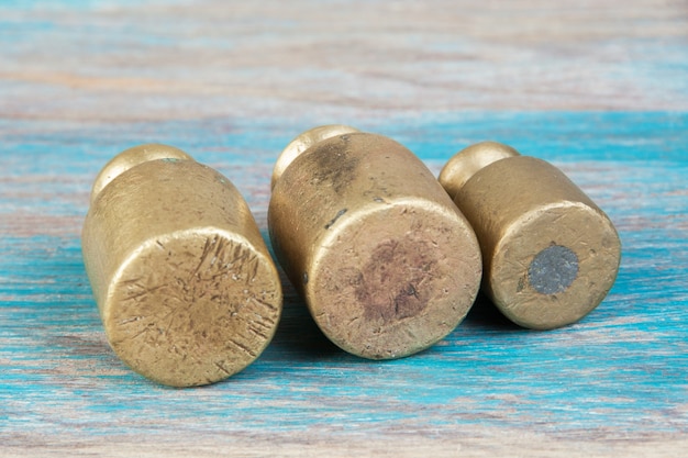 Trois poids en bronze antique pour balances sur fond de bois bleu. Copiez l'espace pour les accessoires de photographie de texte et de nourriture.